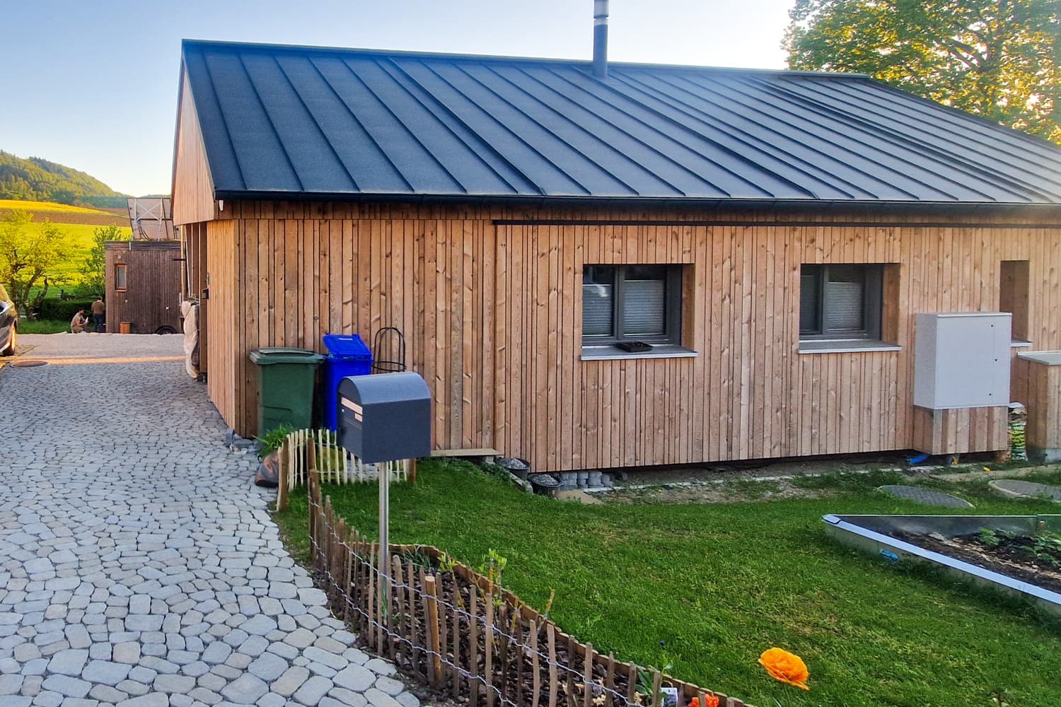 ZINIPI 3-ModulHaus in Gallenkirch AG: Längsseite mit Garten im Abendlicht